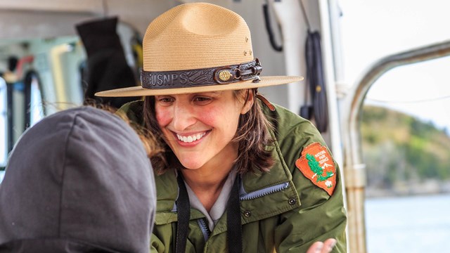 Park ranger speaks with a visitor on a summer boat program.